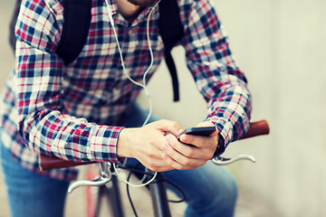 Image showing hipster man in earphones with smartphone and bike