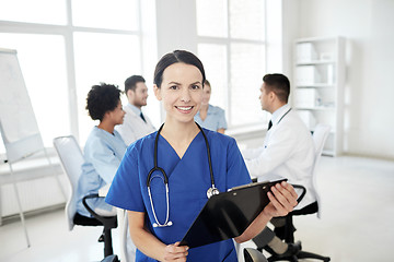 Image showing happy doctor with clipboard over group of medics