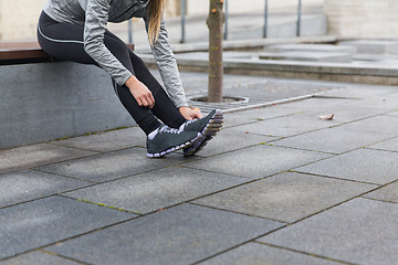 Image showing close up of sporty woman tying shoes outdoors
