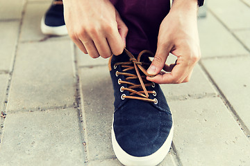 Image showing close up of male hands tying shoe laces on street