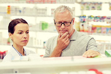 Image showing pharmacist showing drug to senior man at pharmacy