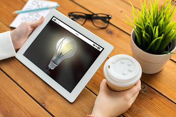 Image showing close up of woman with light bulb on tablet pc