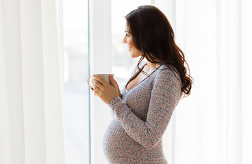 Image showing close up of pregnant woman with tea cup at window