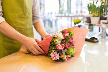 Image showing florist wrapping flowers in paper at flower shop