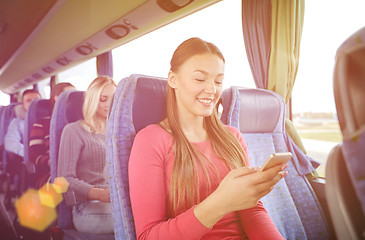 Image showing happy woman sitting in travel bus with smartphone