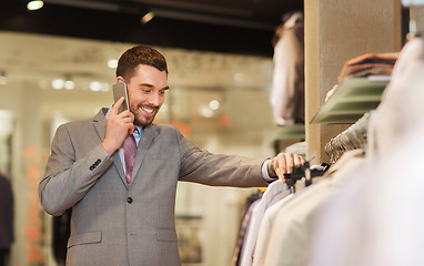 Image showing happy man calling on smartphone at clothing store