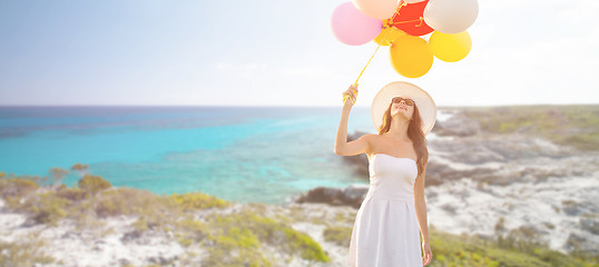 Image showing smiling young woman in sunglasses with balloons