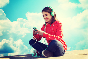 Image showing happy young woman with smartphone and headphones