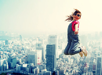 Image showing happy little girl jumping over city background
