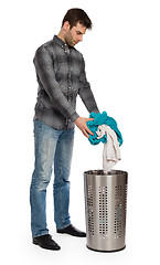 Image showing Young man putting a dirty towel in a laundry basket