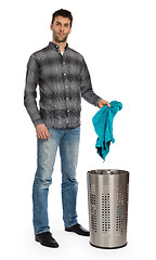 Image showing Young man putting a dirty towel in a laundry basket