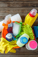 Image showing Plastic bucket with cleaning supplies on wood background