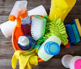 Image showing Plastic bucket with cleaning supplies on wood background