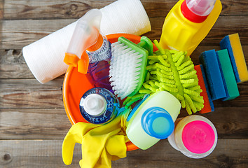 Image showing Plastic bucket with cleaning supplies on wood background