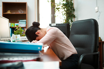 Image showing Tired businesswoman sleeping on the desk.