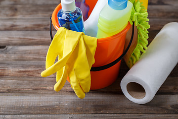 Image showing Plastic bucket with cleaning supplies on wood background