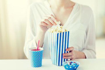 Image showing woman eating popcorn with drink and candies