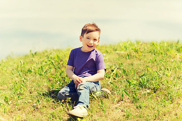 Image showing happy little boy sitting on grass outdoors