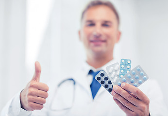 Image showing male doctor with packs of pills