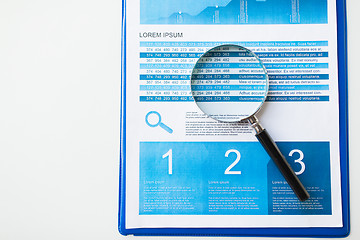 Image showing close up of financial report and magnifying glass