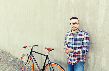 Image showing hipster man in earphones with smartphone and bike