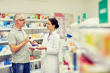 Image showing pharmacist and senior man buying drug at pharmacy