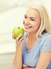 Image showing happy woman eating green apple at home