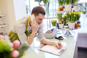 Image showing man with smartphone making notes at flower shop