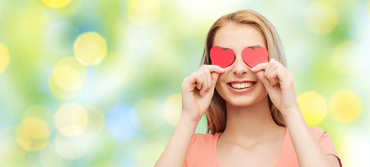 Image showing happy young woman with red heart shapes on eyes