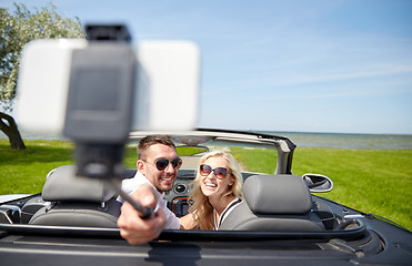 Image showing happy couple in car taking selfie with smartphone