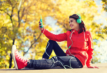 Image showing happy young woman with smartphone and headphones