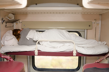 Image showing Passenger train sleeping on the top shelf of the side seats in the second-class carriage turned to the wall