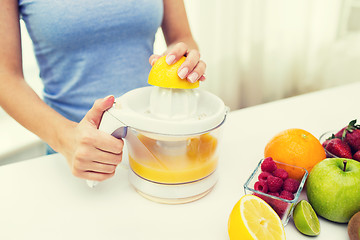 Image showing close up of woman squeezing fruit juice at home