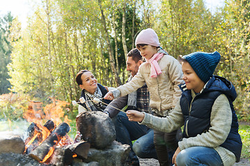 Image showing happy family roasting marshmallow over campfire