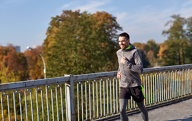 Image showing happy young man running over city bridge