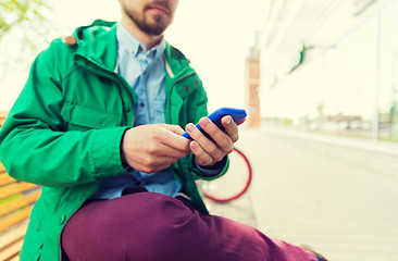 Image showing close up of man with smartphone sitting on bench