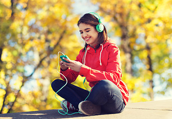 Image showing happy young woman with smartphone and headphones