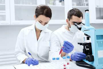 Image showing scientists with clipboard and microscope in lab