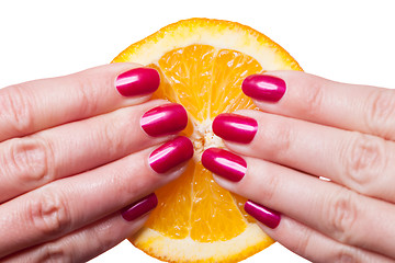 Image showing Hand with manicured nails touch an orange on white