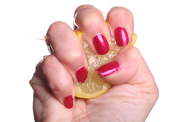 Image showing Hand with manicured nails squeeze lemon on white