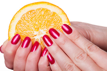 Image showing Hand with manicured nails touch an orange on white