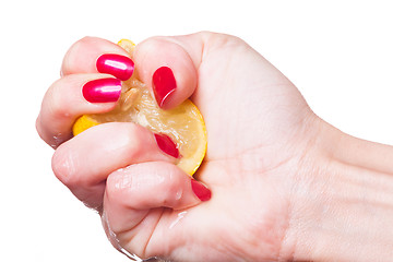 Image showing Hand with manicured nails squeeze lemon on white