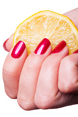 Image showing Hand with manicured nails squeeze lemon on white