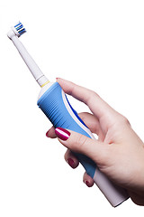 Image showing Hand holds electric toothbrush against white