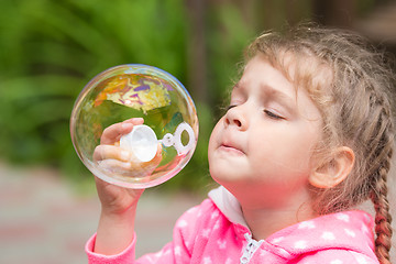 Image showing Five-year girl inflates a large circular bubble