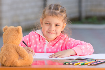 Image showing Girl draws with crayons and smile, he looked into the frame