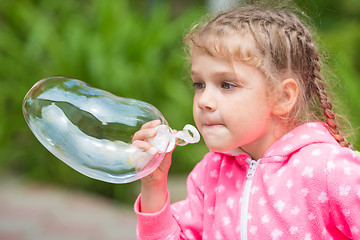 Image showing Five-year girl inflates a large soap bubble