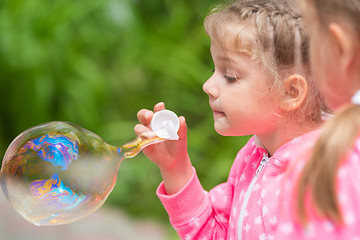 Image showing Five-year girl inflates a large bubble, another girl with interest looks at her