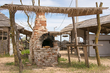 Image showing Old Russian stove under thatched shed in the yard outdoors