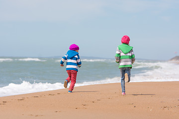 Image showing Two girls run a race on the beach seaside